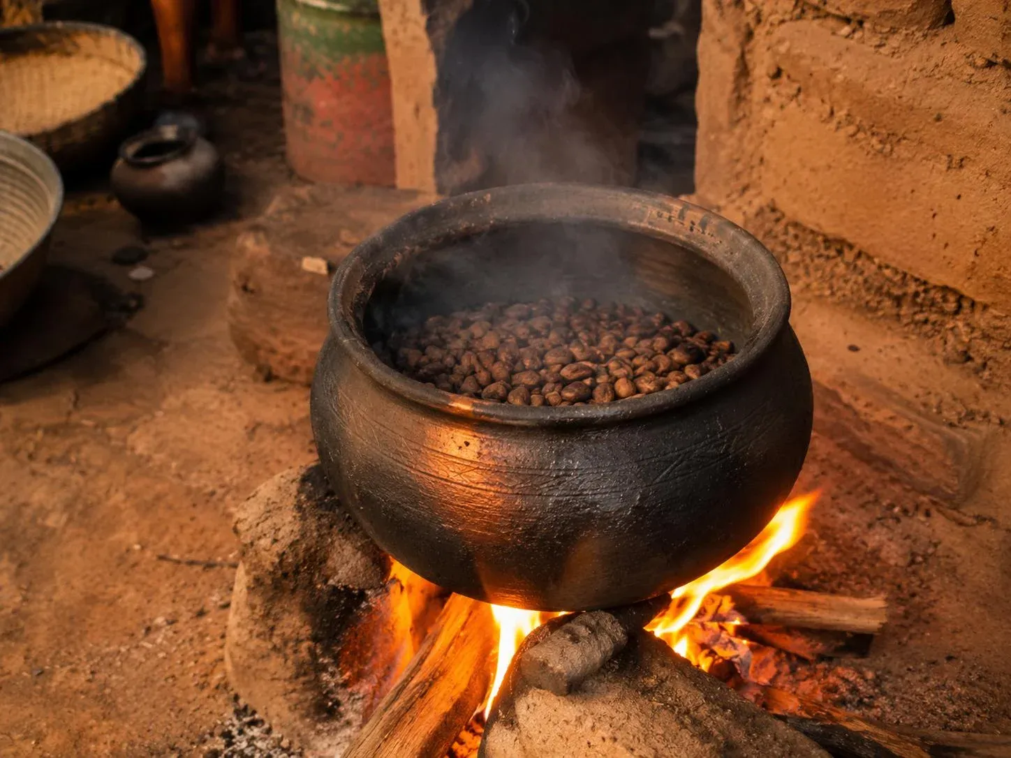 Torréfaction traditionnelle des amandes de karité dans une marmite en terre cuite sur feu de bois
